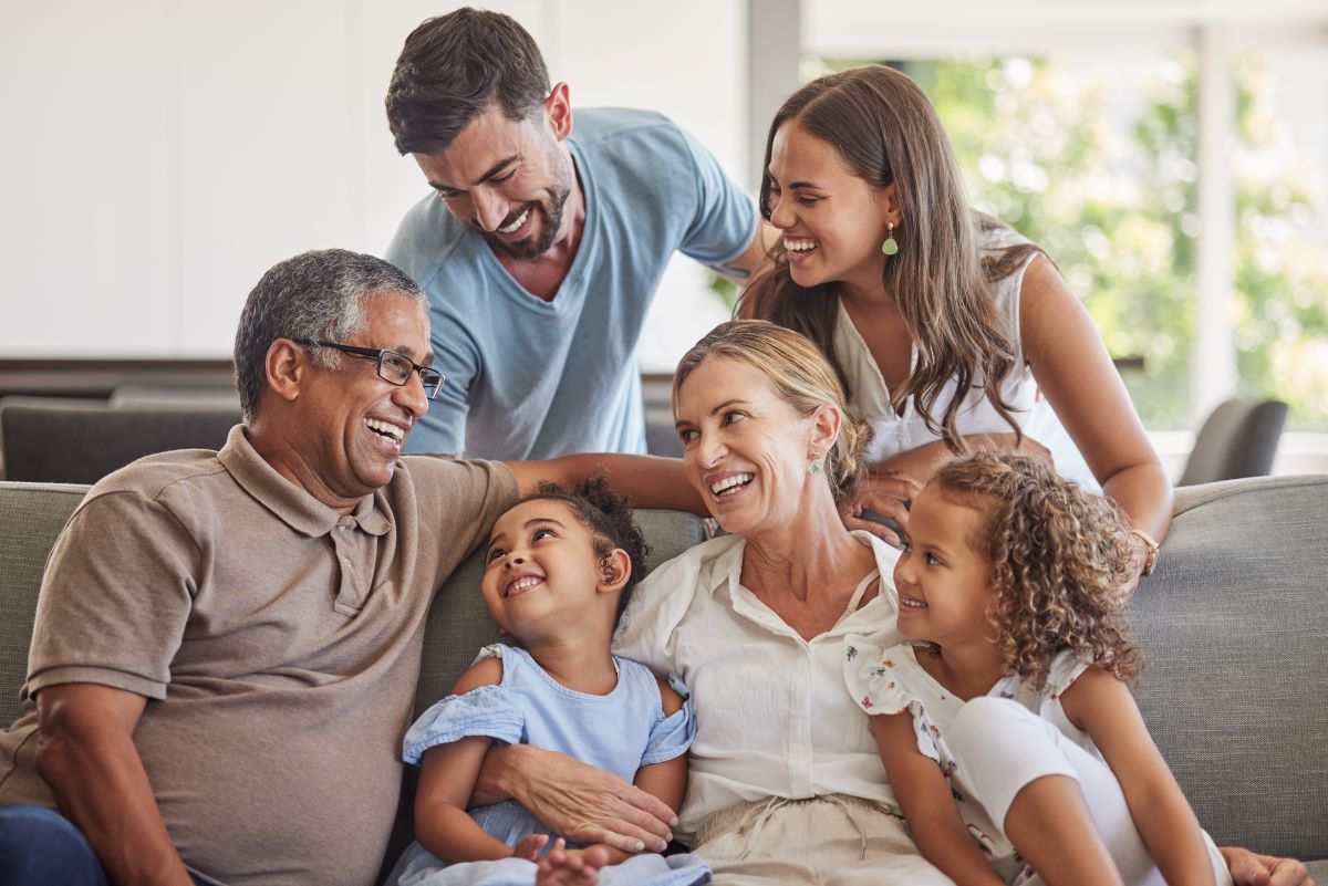 Family sitting on a couch smiling and looking at each other