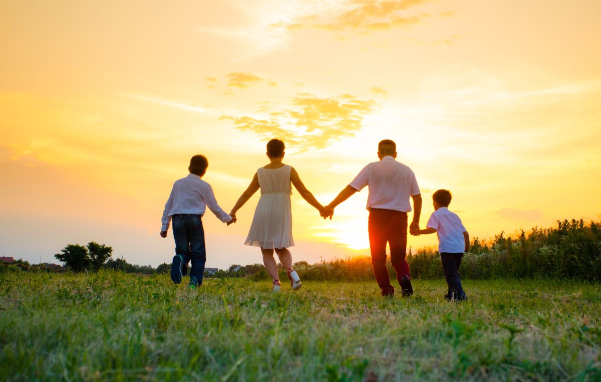 Photo from the back of a family walking into sunset 